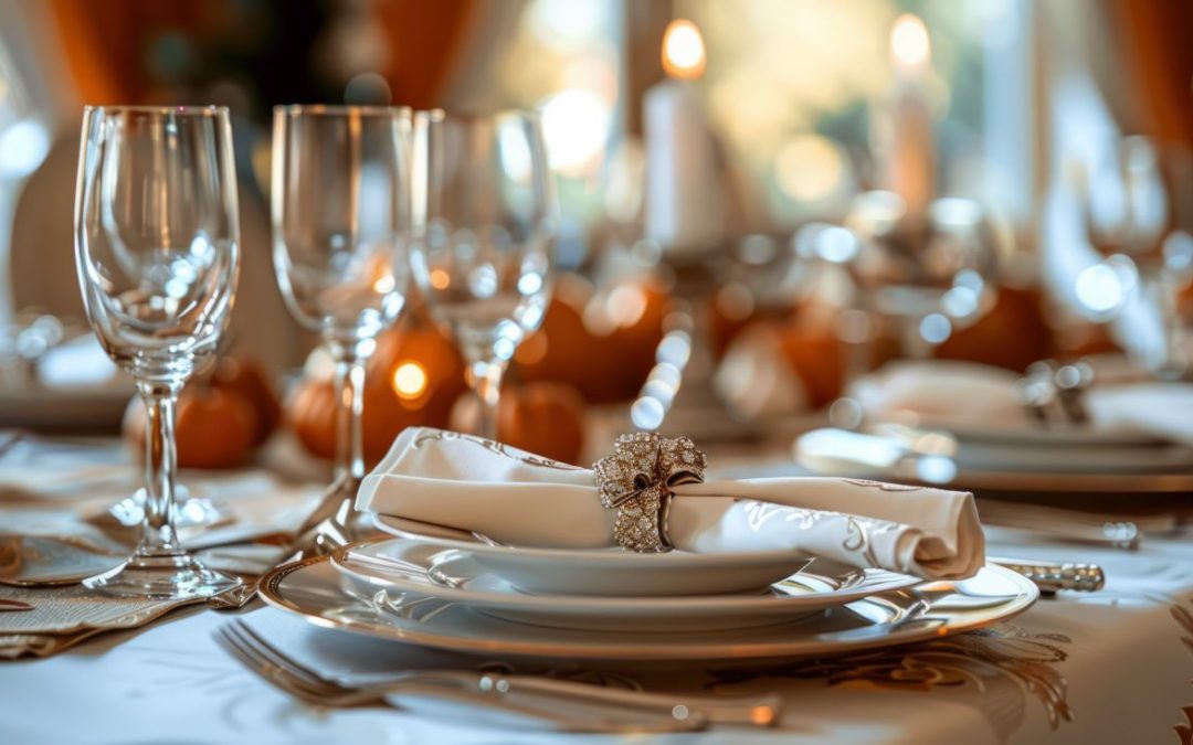 Fall table setting with orange mini pumpkins - white plates with gold accents - candles, leaf themed table cloth - blurred background looking toward window