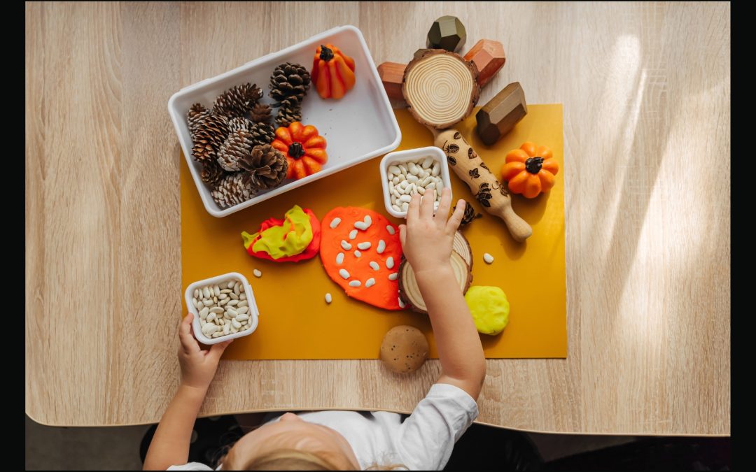 Preschooler at desk - exploring various fall items - pumpkin seeds, playdough, pine cones, pumpkins and more